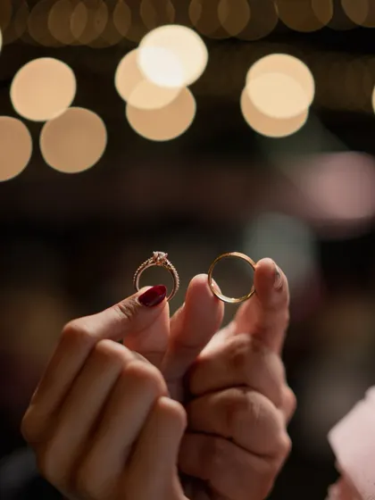 A creative shot of the couple's hands holding their engagement rings up to the light, with a beautiful bokeh background.