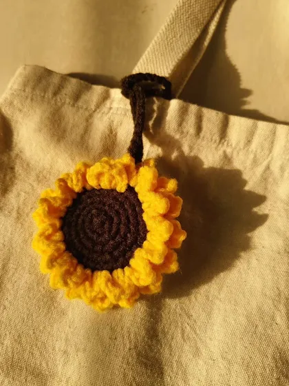 Add a little sunshine to your tote with this crochet sunflower bag charm. It's a beautiful, handmade accessory that brings a cheerful vibe to any bag.