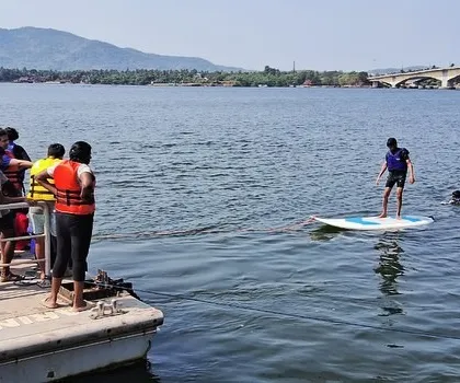 An instructor teaches a student how to balance on a paddleboard from the dock at our Karwar center.
