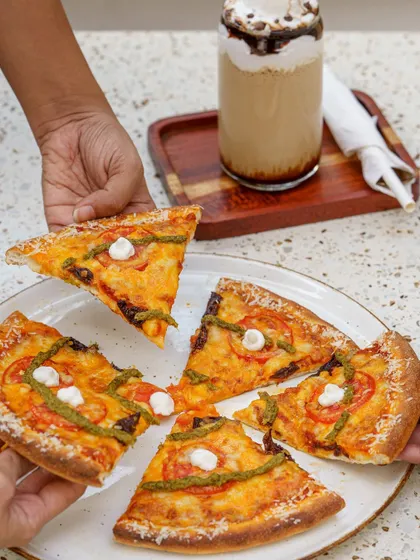 A shared pizza moment at Cafe Zima. This action shot, focusing on people interacting with the food, creates a relatable and inviting scene for a restaurant's social media.