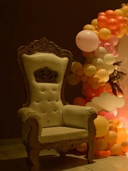 A regal throne chair provided for the mom-to-be at a baby shower. It's a special touch that makes her feel celebrated and provides a great spot for photos.