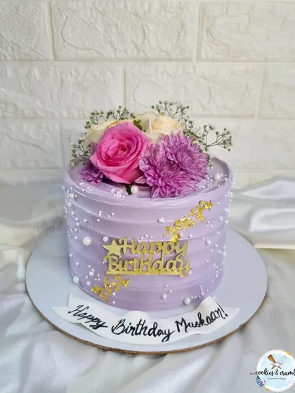 A lovely lavender cake adorned with fresh flowers and gold leaf. The combination of the soft purple hue and the fresh blooms makes for a very pretty and elegant design.