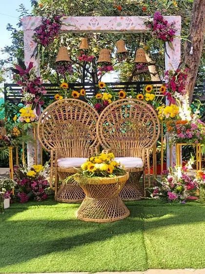 A beautiful Mehendi seating setup with bohemian-style peacock chairs. The backdrop is adorned with sunflowers and wicker bells, creating a rustic and chic vibe.