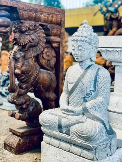 A stone Buddha statue displayed next to an ornate wooden carving, showing the variety of decorative items I can source.