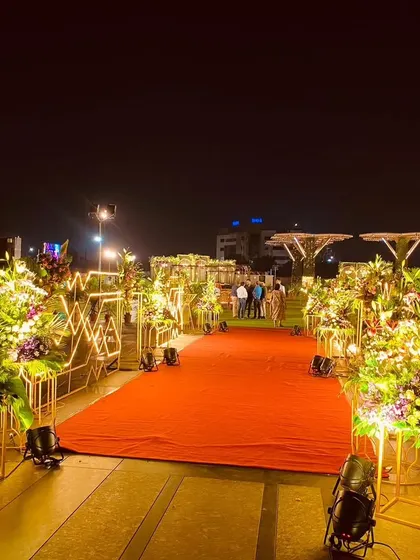For formal corporate events, the entrance sets a tone of prestige. I designed this classic red carpet arrival for a congratulatory ceremony, lined with modern geometric light fixtures and lush floral arrangements to honor the guest of the evening.