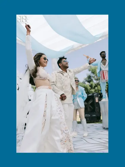 A high-energy moment as the couple makes their entrance. This shot captures their joy and the celebratory atmosphere, with performers in the background adding to the spectacle.