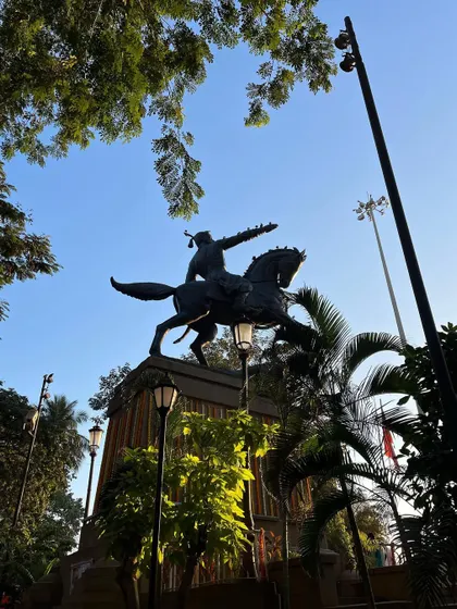 The statue of Chhatrapati Shivaji Maharaj at Shivaji Park, Dadar, framed by trees and morning light during Shivaji Jayanti celebrations.
