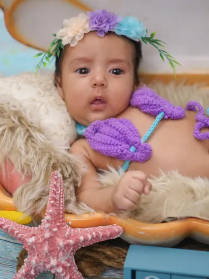 A perfect portrait of our little mermaid. The combination of the crochet outfit, floral crown, and seashell creates a complete and adorable theme.