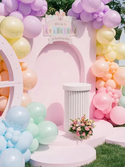 A detailed shot of the main stage's arched backdrop and cake plinth, surrounded by a soft pastel balloon arrangement.