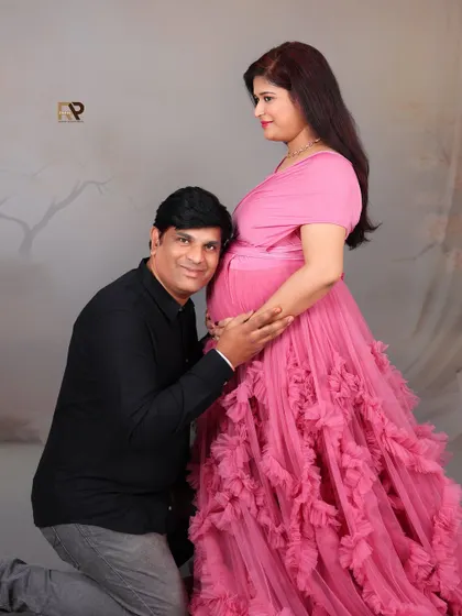 A candid moment of joy. The dad-to-be looks on with love and admiration as his partner cradles her baby bump in a beautiful pink gown.