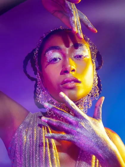A creative beauty portrait using vibrant, multi-colored lighting and glitter makeup. This is for models who want to showcase their ability to handle artistic and expressive concepts.