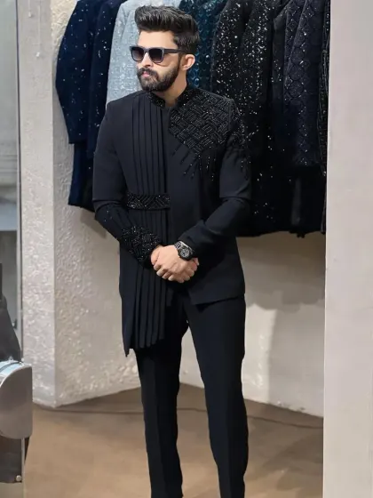 For a modern and fashion-forward look, I designed this black Indowestern set. It features an asymmetrical cut with a pleated drape and geometric beaded embellishments on the shoulder and cuff.
