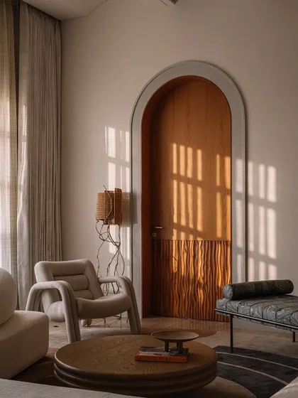 Sunlight filters through the window, casting graphic shadows on the floor and highlighting the textures of the furniture in this serene sitting area.
