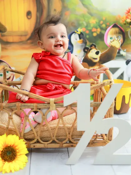 A big, happy laugh from the half-birthday girl. Her bright red dress and the cheerful cartoon backdrop make this a wonderfully vibrant and happy portrait.