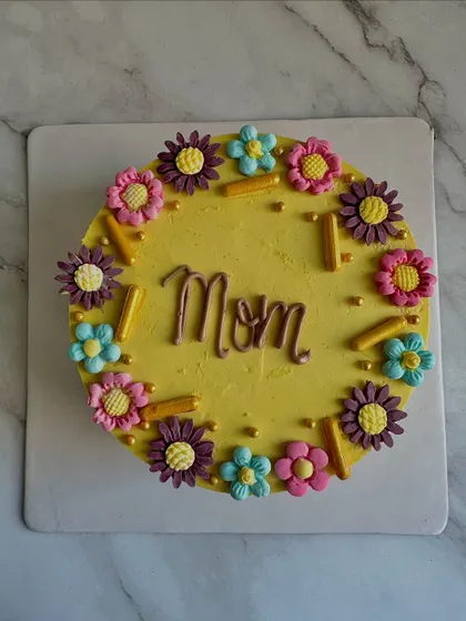 A bright and cheerful yellow cake for Mom, decorated with a garden of colorful, hand-piped buttercream flowers.
