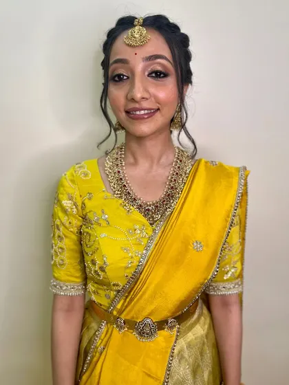 Simplicity and grace define this South Indian look. The makeup is soft and minimal, allowing the bride's natural beauty and the vibrant yellow saree to shine.