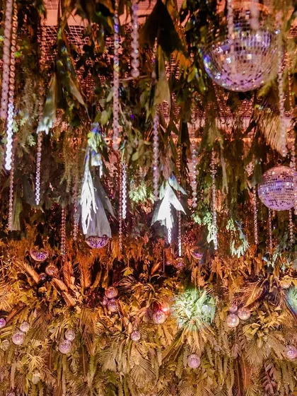 A ceiling completely covered in hanging greenery and disco balls, creating an immersive jungle disco theme for a cocktail night.