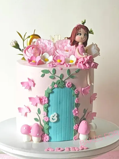 A whimsical fairy house cake with a handcrafted fairy figure, a detailed door, and delicate butterflies. The pink and teal colors create a magical and enchanting look.