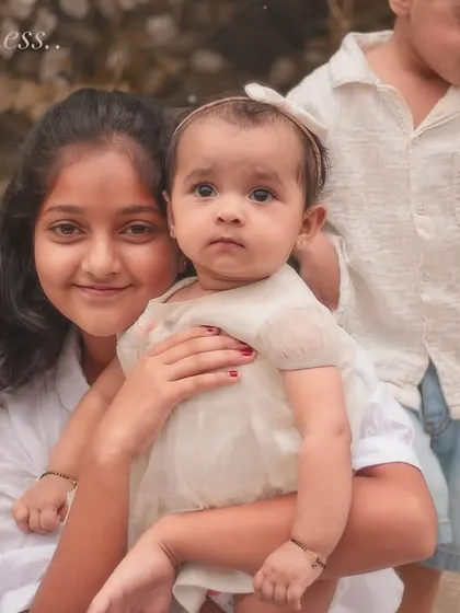 "The tenderness." An older sister holds her baby sibling while her brother plays nearby. This image beautifully captures the different facets of the sibling relationship.