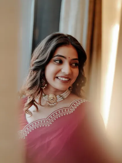 A candid, through-the-curtains shot of a bride, capturing her natural smile and happy glance.