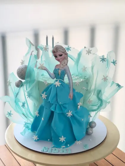An artistic take on the Frozen theme, this Elsa cake is surrounded by a delicate, sail-like structure for a dramatic effect.