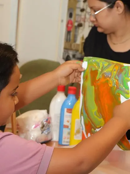 A boy shows off his fluid art creation, one of the creative activities we offer.