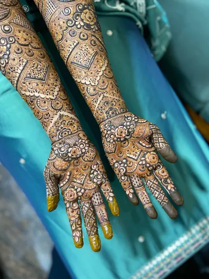 The front view of a bride's full mehendi. Notice the fully covered fingertips, which ensure a deep, dark stain, and the symmetrical patterns on both palms.