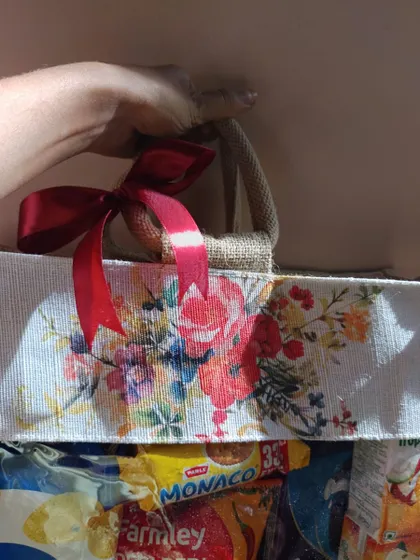 A close-up of the red satin ribbon and floral print on the jute snack bag. These small details add a touch of elegance to a practical welcome gift.
