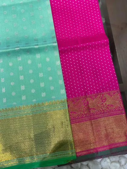 A vibrant pairing of mint green and rani pink. These Kanjeevaram blouse pieces feature distinct butti patterns and rich zari borders.