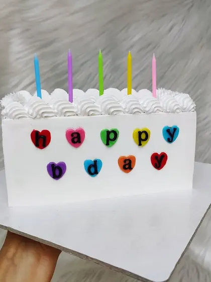 A simple rectangular birthday cake with colorful hearts and birthday candles. A classic and joyful design.