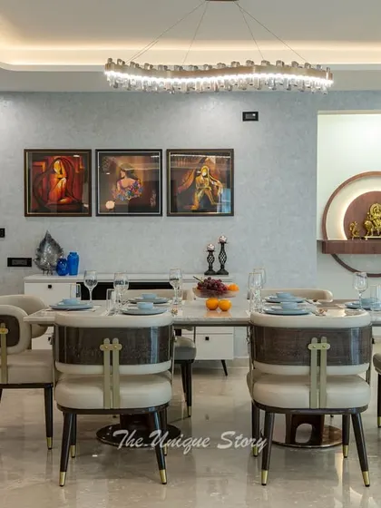 A harmonious dining space that integrates a divine pooja unit. The 8-seater dining set is complemented by a wave-form crystal chandelier, while the backlit Durga pooja unit serves as a serene and spiritual focal point.