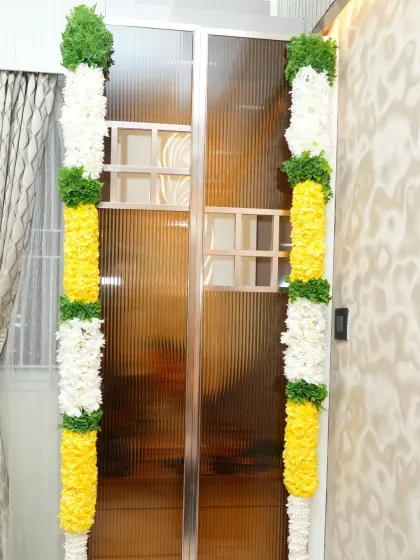 Simple and traditional vertical flower garlands decorating a modern glass door for a housewarming event.