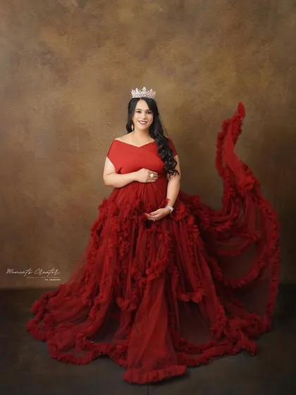 A royal portrait in red. Wearing a tiara and a magnificent ruffled gown, the mom-to-be exudes confidence and grace.