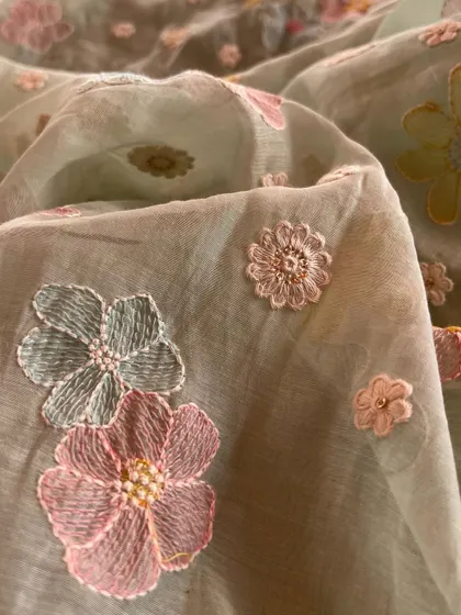 A close-up of our Mul Chanderi fabric with three-dimensional floral embroidery, showcasing the intricate details and beautiful texture.