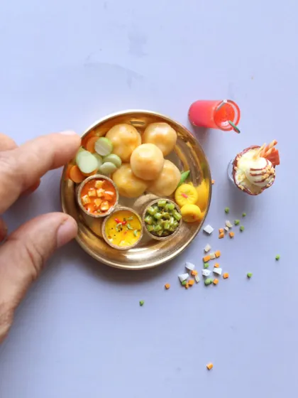 A miniature platter of pooris with various side dishes, a delightful and colorful creation.
