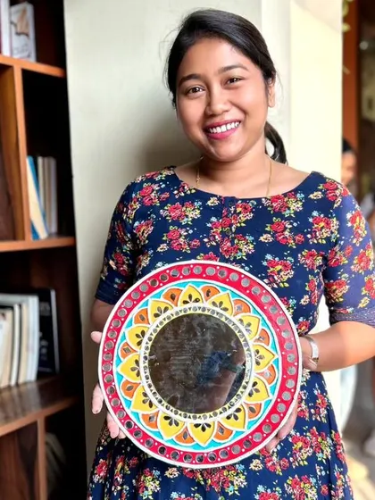 A participant proudly holding her finished Lippan art mirror. The intricate details and mirror work are stunning.