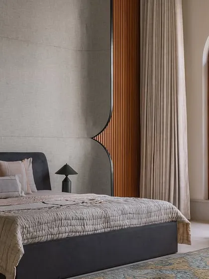 The parent's master suite at Rehethaan is a study in simplicity and thoughtfulness, with a dark bed frame, a comfortable rocking chair, and a large window overlooking the garden.