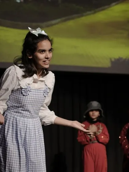 The character of Dorothy from 'The Wizard of Oz' addressing her friends. This image shows a lead actor confidently guiding a scene, demonstrating leadership and clear communication.