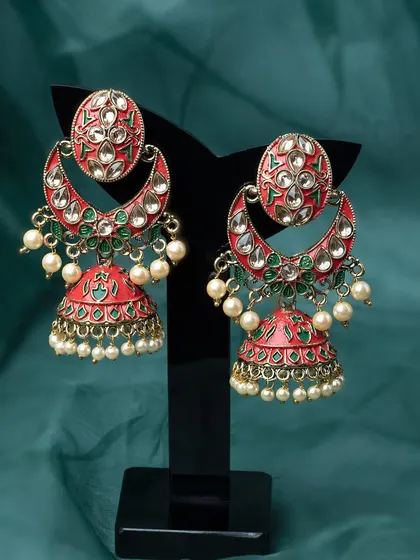A detailed studio shot of traditional red and green jhumka earrings. The clean background and professional display stand make this image perfect for product listings on Amazon or Flipkart.