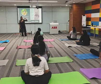 A group of employees at ABB seated in a simple cross-legged position, listening intently during a mindfulness workshop. Creating a calm and focused environment is possible even in an office.