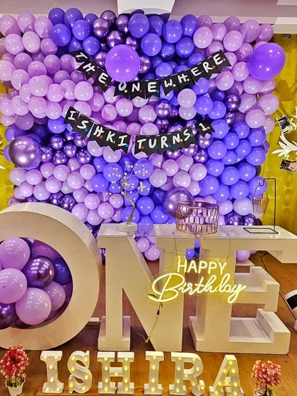 This "Friends" inspired theme, "The One Where Ishika Turns One," features a massive purple balloon wall and a custom banner.
