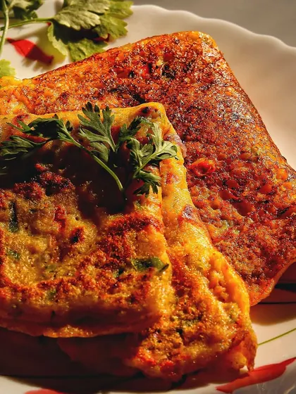 A close-up of the moong dal chilla, focusing on its crispy texture and the fresh cilantro garnish. This shot is all about making the food look as tasty as possible.