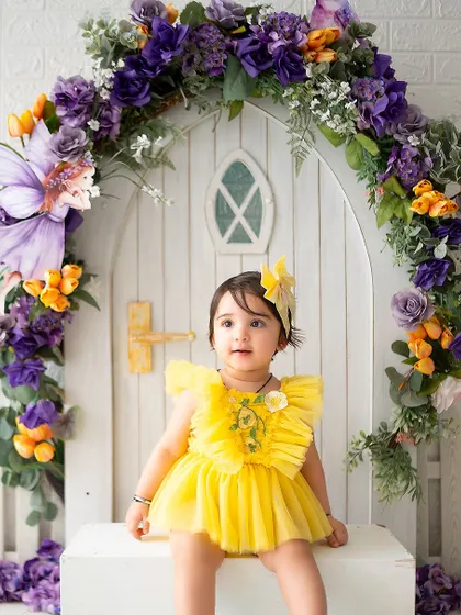 A sweet portrait of the birthday girl sitting in front of her magical fairy house.