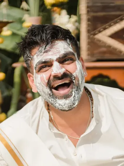The groom's face is completely covered in white paste, and his joyful laugh is contagious. This shot captures the hilarious and messy side of Haldi celebrations.