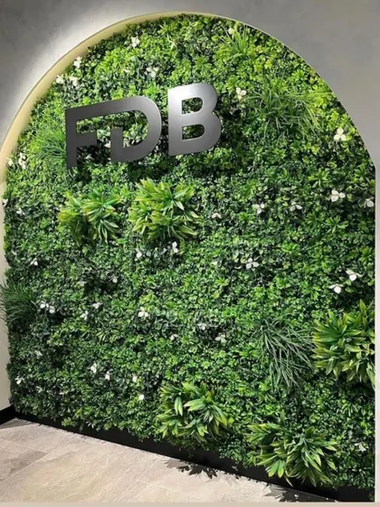 An elegant artificial vertical garden installed in an arched alcove for an office reception area, complete with company branding.