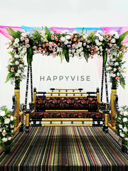 A beautifully decorated swing or 'jhoola' for a cradle ceremony. The frame is adorned with white and pink flowers, making it a perfect centerpiece for the event.