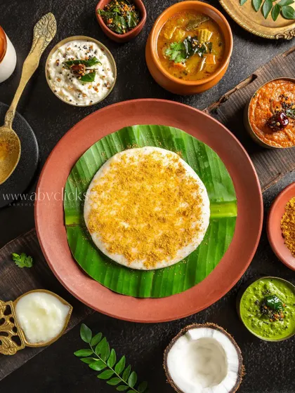 A Ghee Podi Uttapam, a thick savory pancake, presented on a banana leaf with traditional South Indian accompaniments.