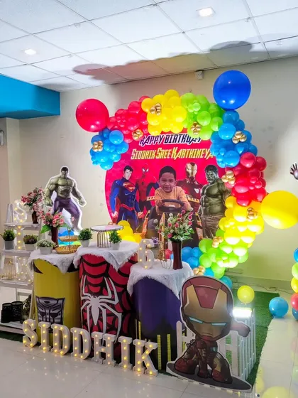 Another view of the superhero party, showing the colorful balloon arch and character cutouts.