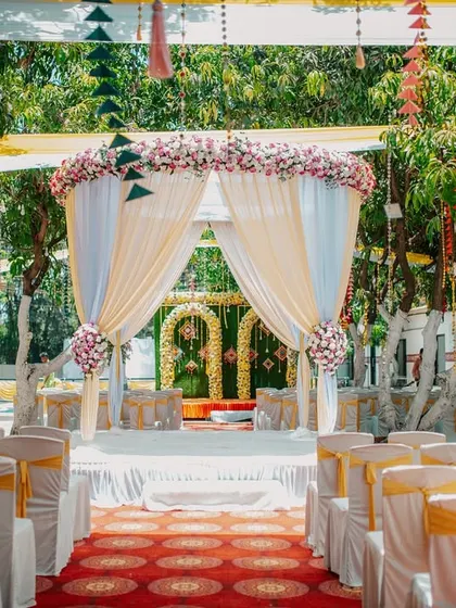 The wedding mandap and seating arrangement for an outdoor ceremony, beautifully decorated with flowers.