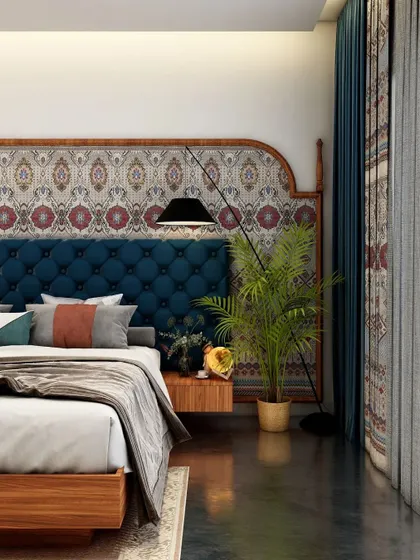 This bedroom showcases a bold design with a tufted blue velvet headboard set against a traditional patterned wallpaper. The mix of rich textures and colors creates a vibrant and eclectic yet cozy atmosphere.